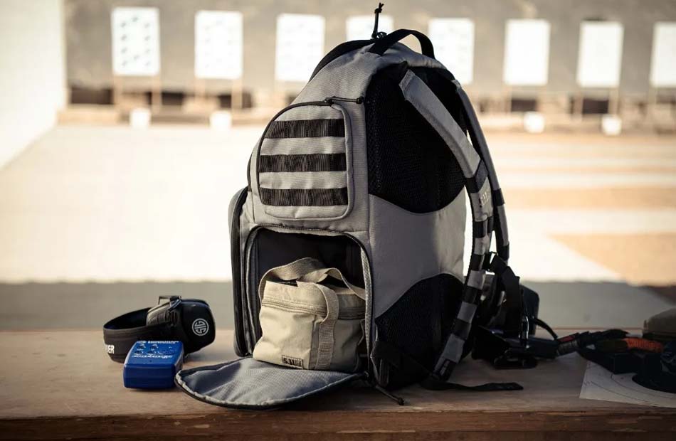 A detailed image of the new 5.11 Tactical SIG Sauer Range Ready Backpack, launched at the 2025 SHOT Show, showcasing its rugged design and thoughtful features. The backpack is crafted from durable materials and includes a dedicated handgun compartment, ample storage for ammunition, and multiple organizational pockets for range essentials. Its padded shoulder straps and adjustable fit provide exceptional comfort, even when carrying a fully loaded bag. The sleek, professional appearance reflects the collaboration between 5.11 Tactical and SIG Sauer, offering both style and practicality. Designed for range trips and outdoor shooting sessions, this backpack ensures users can transport their gear securely and efficiently. The high-quality construction and smart layout make it an ideal choice for serious shooters who value organization and reliability.